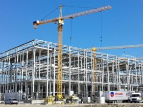 Electric vehicle factory construction with Rivian trucks nearby