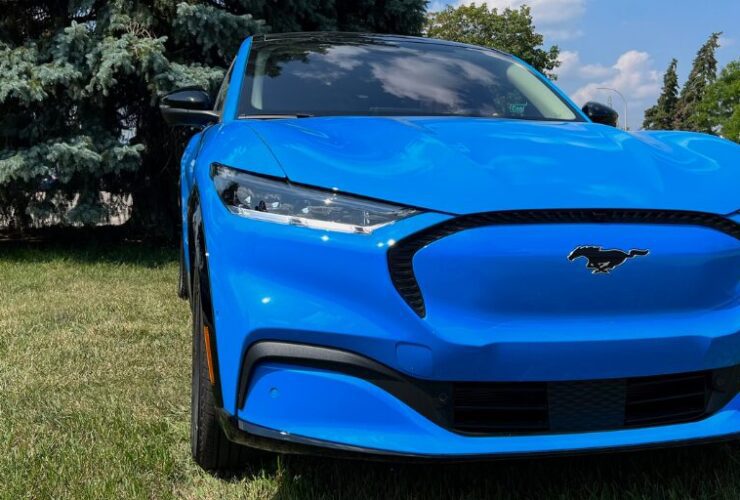 Blue Mustang Mach-E parked by bush.